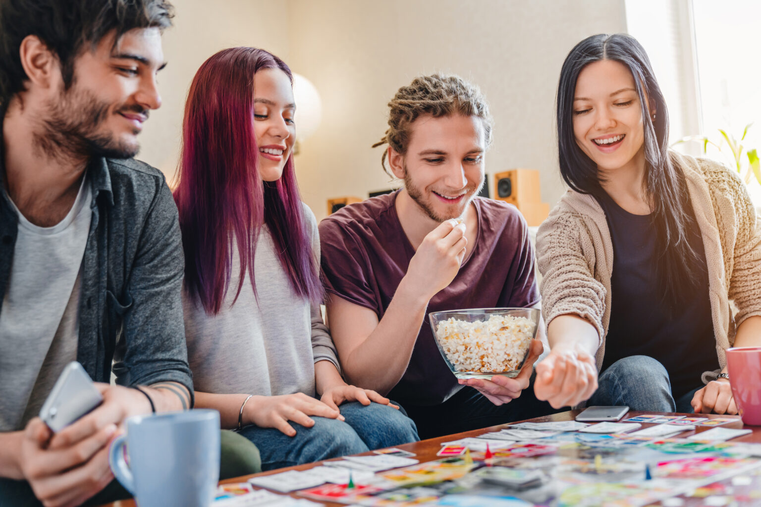 kodukindlustus, sõbrad istuvad diivanil, söövad popcorni ja mängivad monopoly.