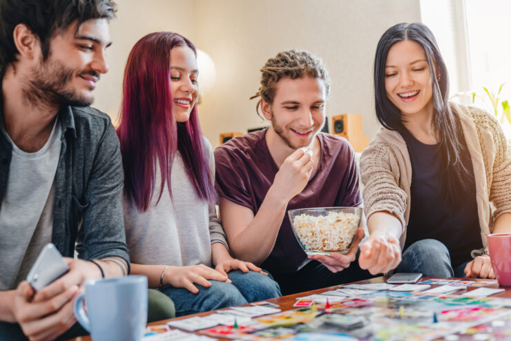 kodukindlustus, sõbrad istuvad diivanil, söövad popcorni ja mängivad monopoly.