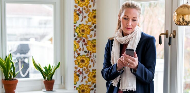 Naine on oma kodus, telefon käes. Tal on tõsine nägu peas.