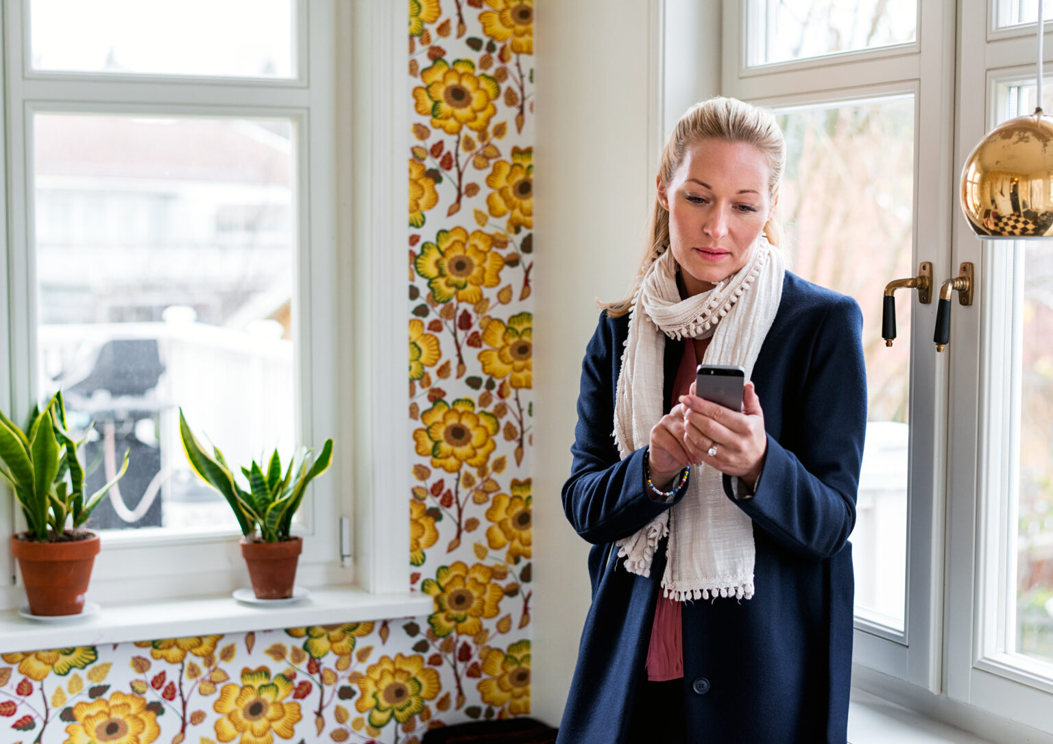 naine vaatamas oma mobiiltelefoni. Ta seisab värvilises kohvikus.