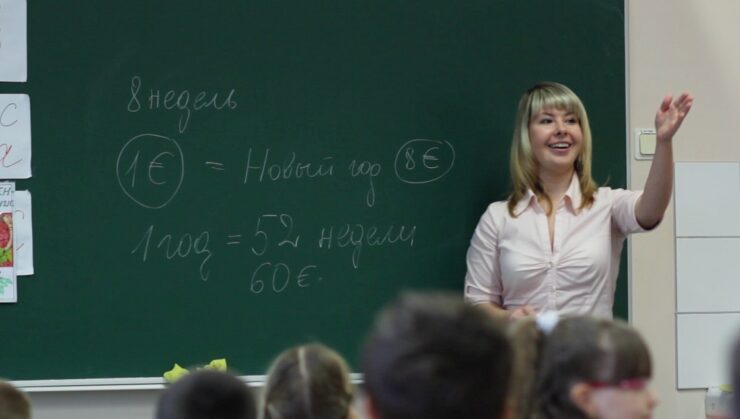 Õpetaja klassiruumis tahvli ees.