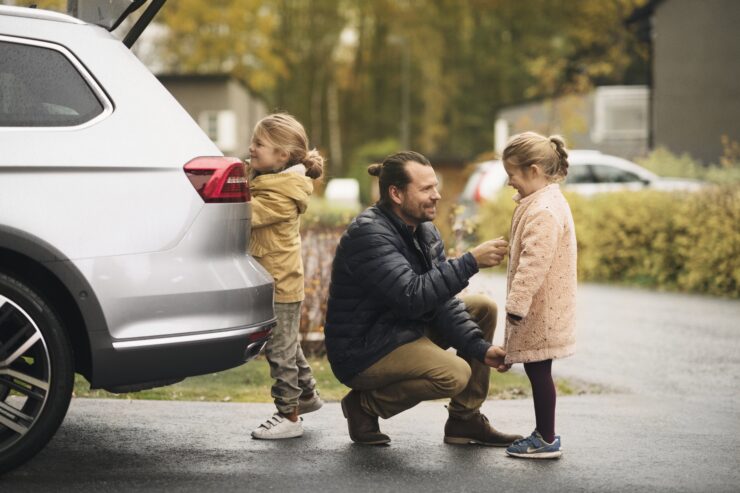 Isa kahe tütrega autosse asju pakkimas. Sügisene ilm on.