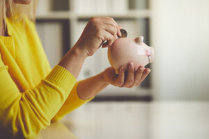 Woman inserts a coin into a piggy bank,