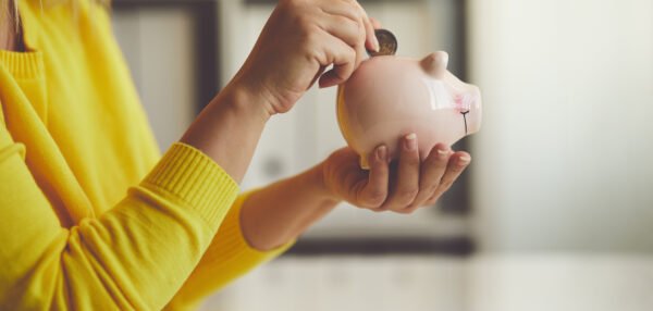 Woman inserts a coin into a piggy bank,