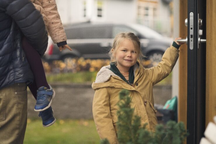 Väike tüdruk minemas koju ta hoiab käega ukselingist kinni.