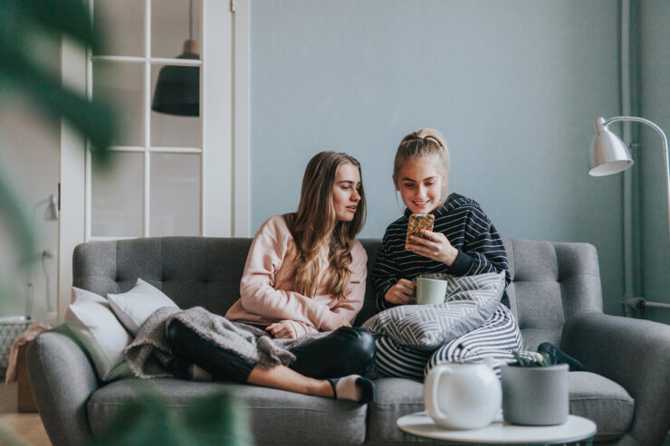 biomeetria: Kaks noort vaatamas telefonist midagi. Nad istuvad elutoas diivanil.