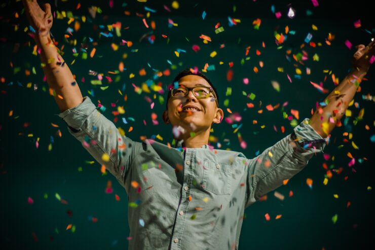 Mees pidutsemas, ta ümber on confetti ja tal on käed üleval.