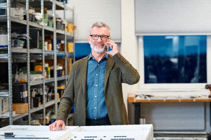 mees kontoris, tal on telefon ja ta helistab naerusuiselt kellelegile.