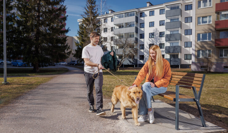 Mees ja naine jalutavad koos kortermajade ees koeraga