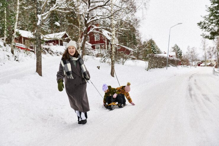 Ema ja lapsed kelgutavad talvises Rootsi külas.