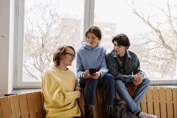 Noored istuvad koolis pingi peal ja vaatavad telefoni.