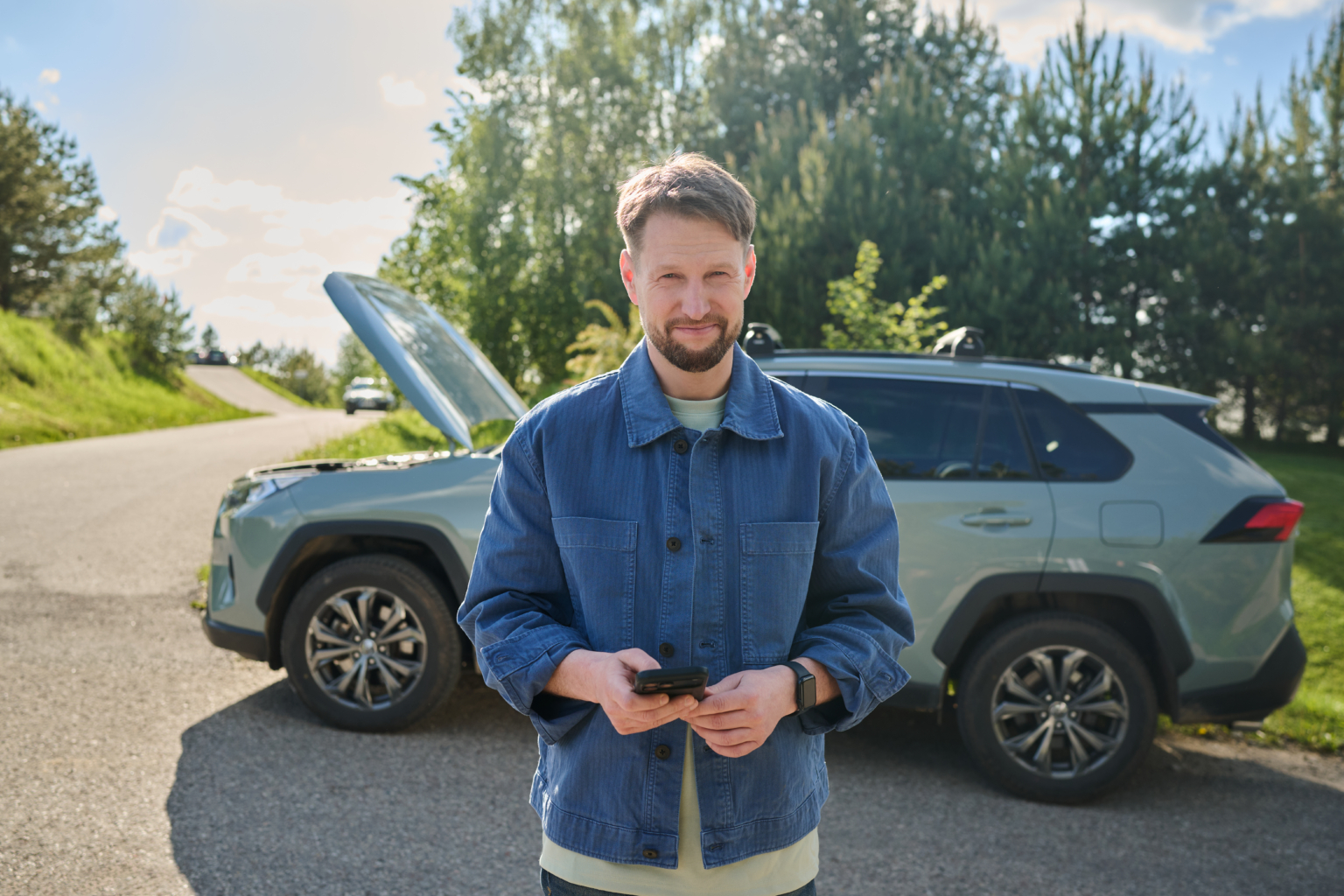 Auto seisab teeääres kapott lahti ja mees seisab esiplaanil telefon käes
